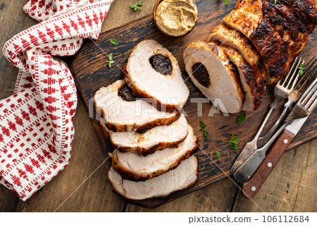 Roasted pork loin stuffed with prunes on wooden board 106112684