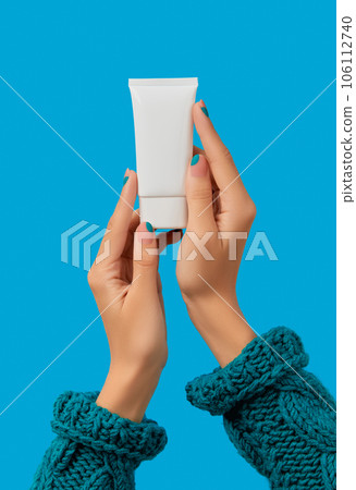 Womans hand with blue manicure holding white tube. Care products 106112740