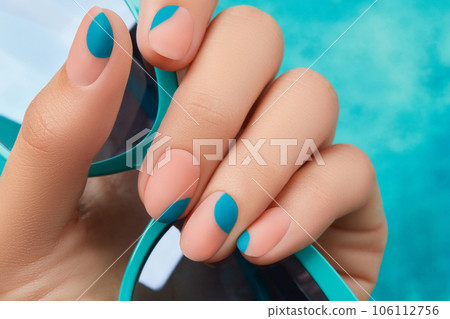 Close up womans hand with summer manicure on blue background. Manicure design trends Close up womans hand with summer manicure on blue background. Manicure design trends 106112756