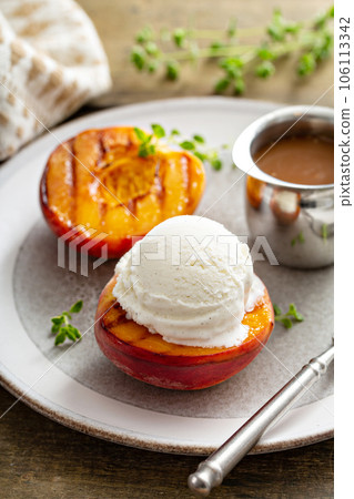 Grilled peaches with ice cream and caramel sauce, summer dessert Grilled peaches with ice cream and caramel sauce, summer dessert 106113342
