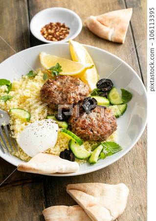 Herb turkey patties served with couscous and fresh salad Herb turkey patties served with couscous and fresh salad 106113395