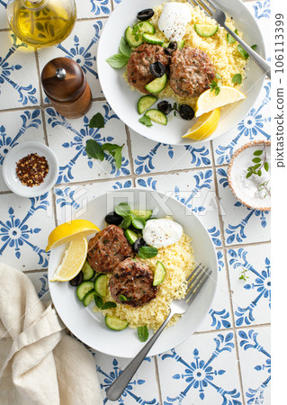 Herb turkey patties served with couscous and fresh salad 106113399