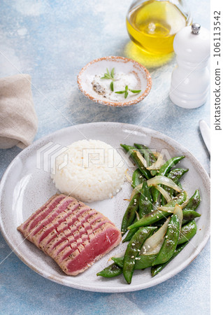 Seared tuna steak with white rice and green peas Seared tuna steak with white rice and green peas 106113542