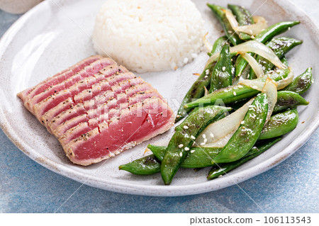 Seared tuna served with rice and green peas 106113543