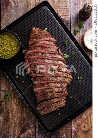 Grilled flank steak with chimichurri sauce on a grill pan 106113610