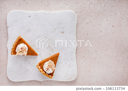 Pumpkin pie slices topped with whipped cream 106113734