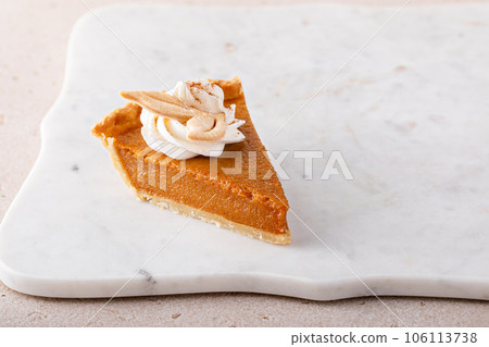Pumpkin pie slice topped with whipped cream 106113738