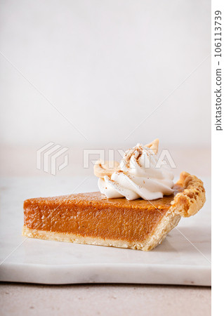Pumpkin pie slice topped with whipped cream 106113739