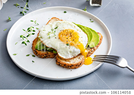 Avocado toast on a toasted multigrain bread with a fried egg 106114058