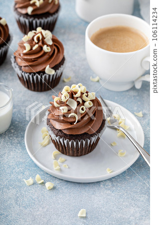 Dark chocolate cupcakes with whipped ganache frosting and white chocolate curls 106114234