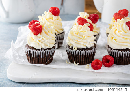 Chocolate cupcakes with white chocolate frosting and raspberries Chocolate cupcakes with white chocolate frosting and raspberries 106114245
