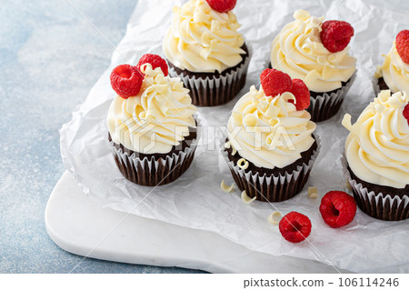Chocolate cupcakes with white chocolate frosting and raspberries Chocolate cupcakes with white chocolate frosting and raspberries 106114246