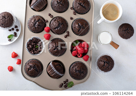 Chocolate muffins in a muffin pan with raspberries 106114264