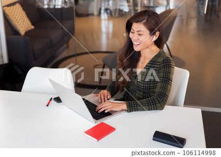 Laughing lady with netbook in workspace 106114998