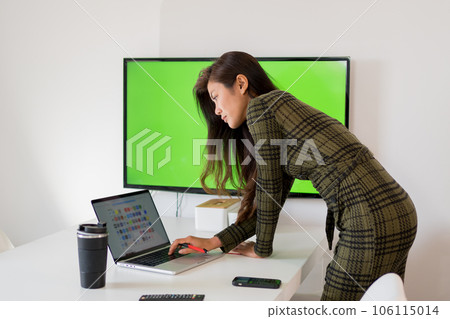 Lady browsing computer near display with chromakey in workplace 106115014