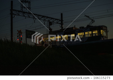 A tram passing a railroad crossing on the embankment just after sunset A tram passing a railroad crossing on the embankment just after sunset 106115273