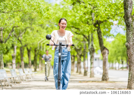 美麗的綠樹成蔭的街道上，一位年輕可愛的女士在電動滑板上清爽地奔跑 | 電動滑板圖片 106116863