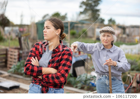 Two disappointed young and old female neighbors quarreling while digging garden during daytime in April 106117200