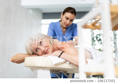 Aged woman relaxing in spa center during professional back massage 106117201