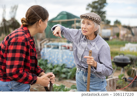 Two disappointed young and old female neighbors quarreling while digging garden during daytime in April Two disappointed young and old female neighbors quarreling while digging garden during daytime in April 106117220
