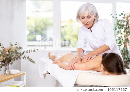 Elderly woman doing back massage to young woman 106117267
