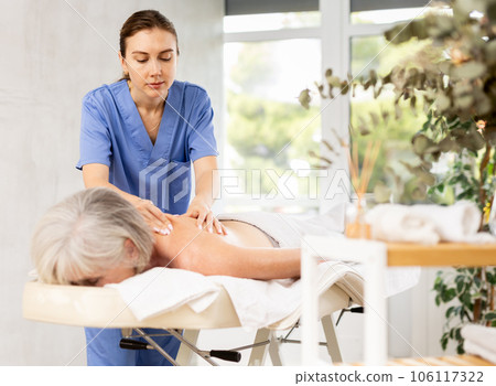 Young woman doing back massage to elderly woman Young woman doing back massage to elderly woman 106117322