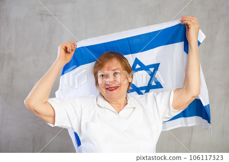 Happy senior woman waving national flag of Israel 106117323