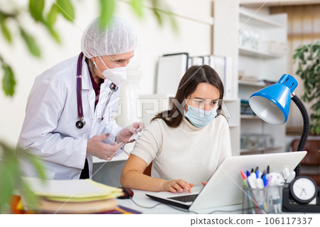 Doctor in white coat and protective mask giving vaccine injection to woman manager 106117337