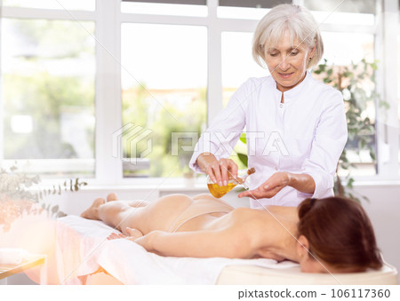 Elderly woman giving oil massage to young woman Elderly woman giving oil massage to young woman 106117360