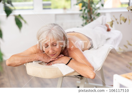 Elderly woman lies on massage table in salon 106117510