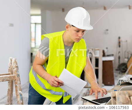 Teenage boy using laptop and checking documentation in construction site Teenage boy using laptop and checking documentation in construction site 106117563
