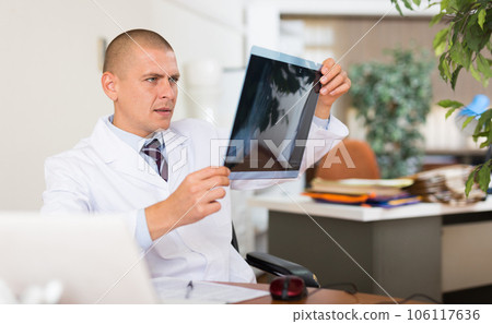 Male doctor examining x-ray at clinic Male doctor examining x-ray at clinic 106117636
