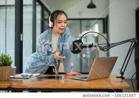 A beautiful Asian female radio host or radio journalist is speaking into a microphone A beautiful Asian female radio host or radio journalist is speaking into a microphone 106121897