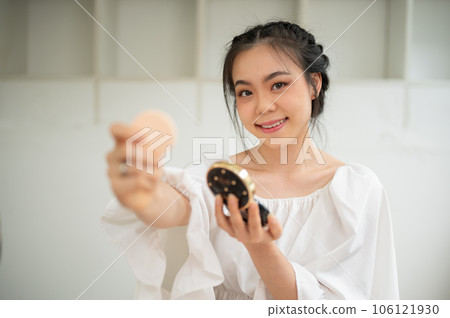 An attractive Asian female beauty influencer showing her new cosmetic product to a camera 106121930