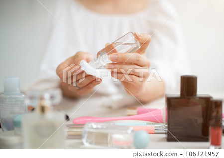 Close-up image of a woman dropping makeup remover on a cotton pad to clean her face Close-up image of a woman dropping makeup remover on a cotton pad to clean her face 106121957