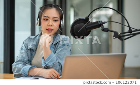 A beautiful Asian female radio host speaks into a microphone, sharing interesting news 106122071