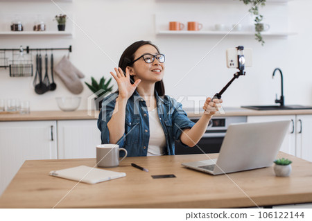 Female taking photo via smartphone held by selfie stick 106122144