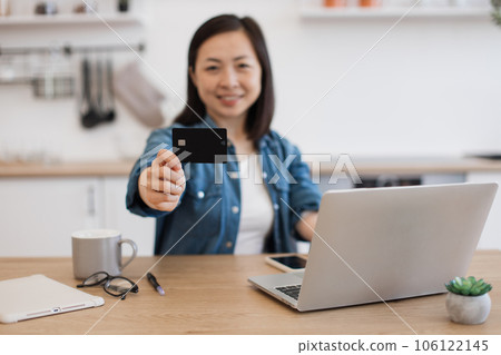 Black payment card held by asian lady working at home 106122145