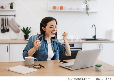 Woman with debit card showing yes gesture behind computer 106122163