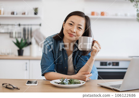 Asian woman drinking water after snack while teleworking 106122686