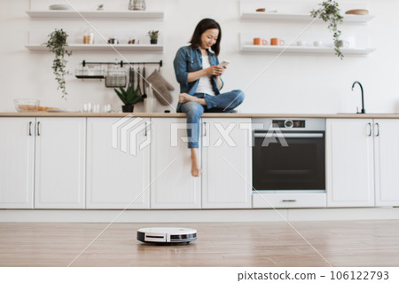 Asian woman monitoring vacuum cleaner on cell phone Asian woman monitoring vacuum cleaner on cell phone 106122793