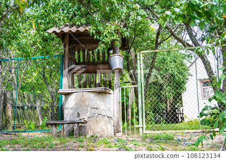Old well with iron bucket on long forged chain for clean drinking water Old well with iron bucket on long forged chain for clean drinking water 106123134