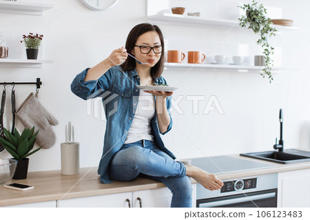 Female cook tasting vegetarian meal in kitchen interior 106123483
