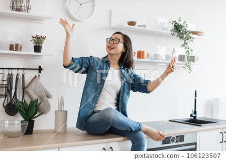 Woman sitting on kitchen and having video call on smartphone Woman sitting on kitchen and having video call on smartphone 106123507