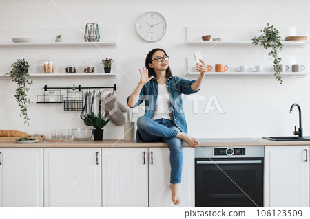 Asian female taking selfie on mobile in apartment interior Asian female taking selfie on mobile in apartment interior 106123509