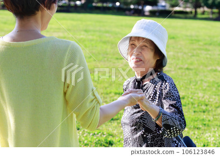 Parent and child holding hands with a senior woman and walking in nature Parent and child holding hands with a senior woman and walking in nature 106123846