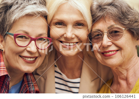 Portrait of happy middle age women hug and look at camera on city street. Female friendship 106126441