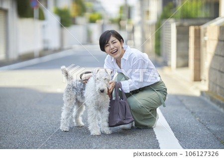 A young woman walking in a residential area with her dog Wire Fox Terrier A young woman walking in a residential area with her dog Wire Fox Terrier 106127326