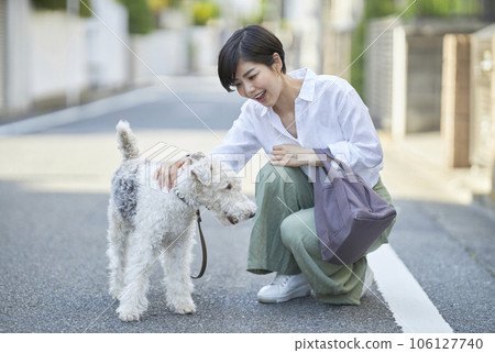 A young woman walking in a residential area with her dog Wire Fox Terrier A young woman walking in a residential area with her dog Wire Fox Terrier 106127740