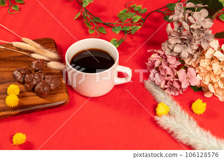 Coffee and chocolate placed on a red carpet with wintery dried flowers 106128576